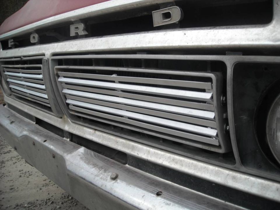 Close-up of a 1973 Ford truck grille with the 'FORD' emblem visible above