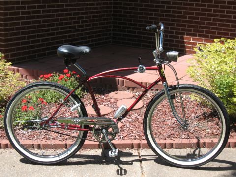 1994 Ford Bronco - A red cruiser bicycle is parked outside a brick building with red flowers and green bushes nearby.