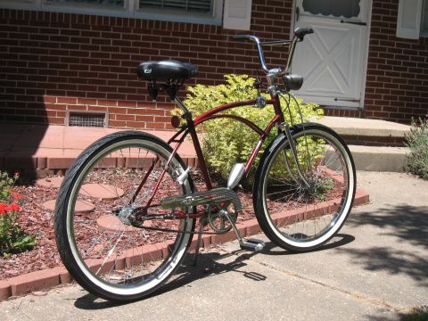 1994 Ford Bronco - A red cruiser bicycle with whitewall tires and chrome handlebars is parked on a sidewalk in front of a brick house.