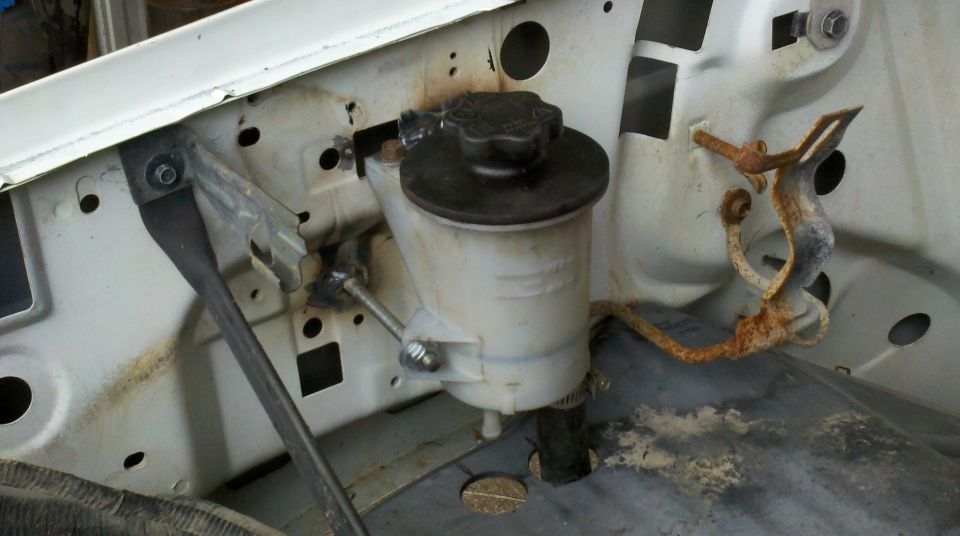 Power steering fluid reservoir mounted in engine bay, some rust on bracket