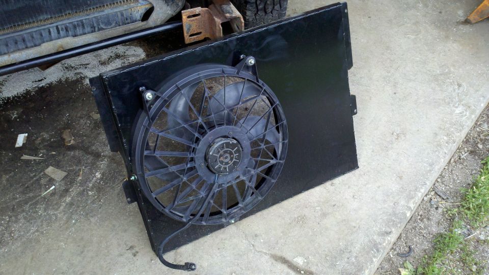 Radiator fan assembly with black shroud and wiring, resting on concrete