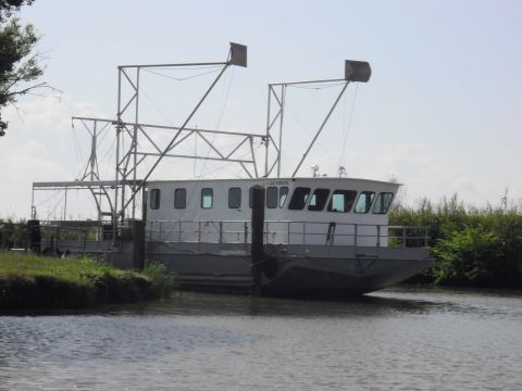 1993 Ford Bronco - A gray boat with a white superstructure is docked near a grassy bank under a clear sky.