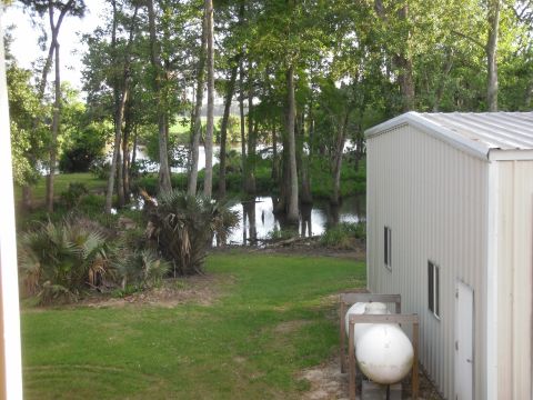 1993 Ford Bronco - A scenic view of a waterway surrounded by trees, with a metal building and storage tanks in the foreground.