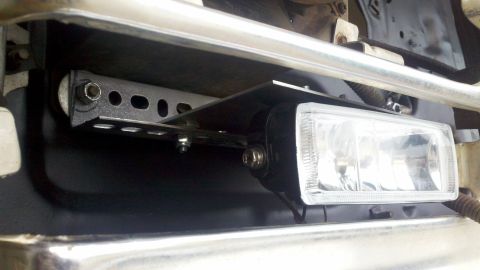 1978 Ford Bronco - Close-up of an aftermarket fog light installation on a vehicle's front end.