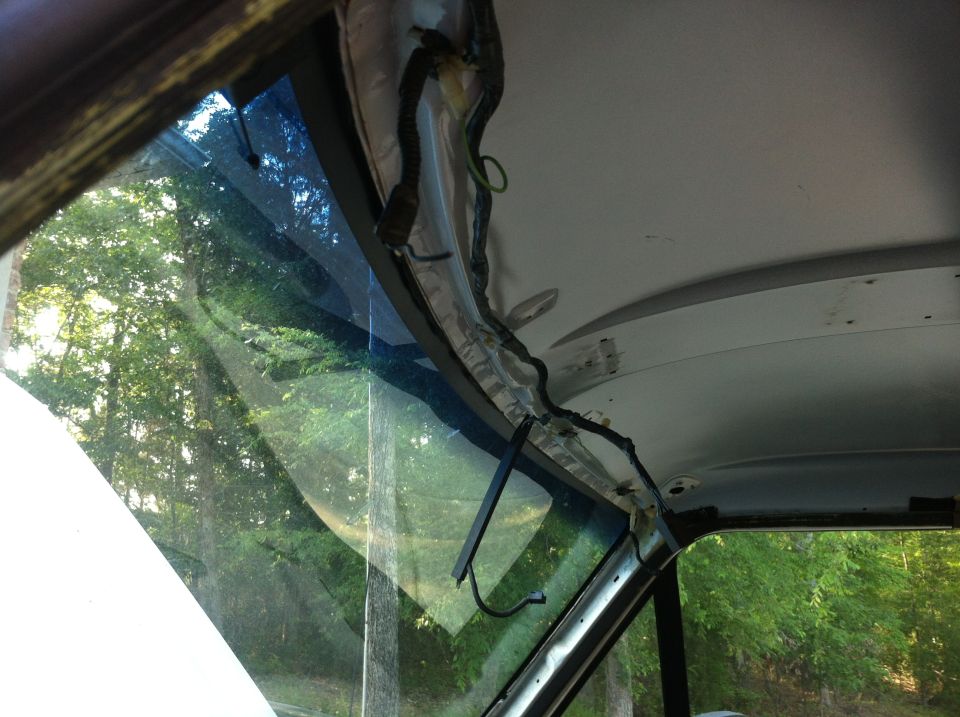 Overhead console wiring exposed inside a vehicle, with trees visible through the windshield