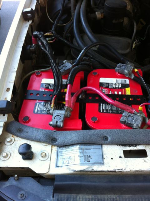 1996 Ford Bronco - Close-up view of dual red Optima batteries installed in a vehicle's engine compartment.