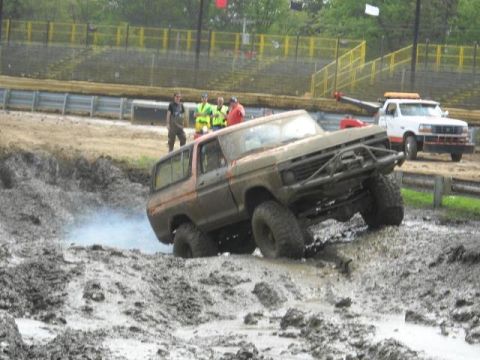 1978 Ford Bronco - This 1978 Ford Bronco is shown tackling a challenging muddy terrain, while a tow truck waits nearby.