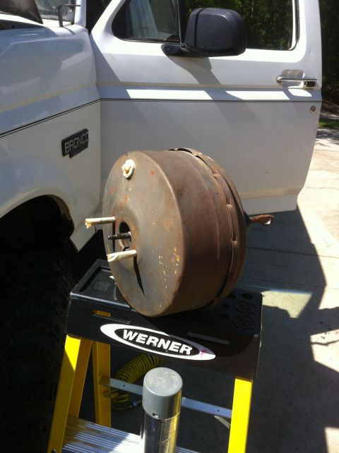 1996 Ford Bronco - A brake booster is removed from a white Ford Bronco and placed on a yellow stand.