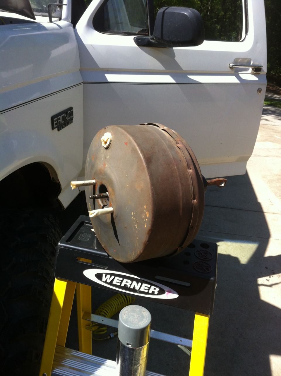 White Bronco with brake booster removed and sitting on a stand