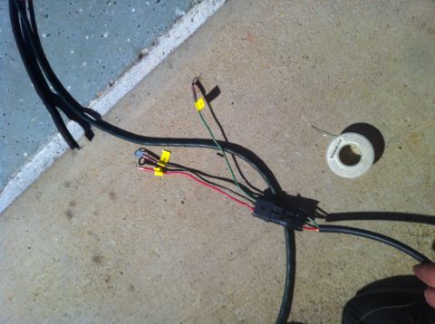 1996 Ford Bronco - Close-up of an automotive wiring harness with exposed wires and connectors on a concrete surface.