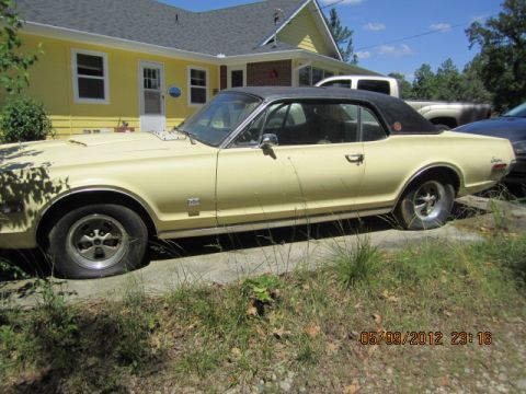 1968 Mercury Cougar - A side view of a vintage Mercury Cougar with a black vinyl roof sits parked in front of a house.