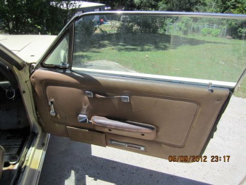 1968 Mercury Cougar - Close-up of a car's interior door panel, showing the brown upholstery and chrome hardware.