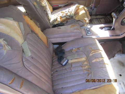 1968 Mercury Cougar - The interior of a car shows significant wear and tear on the seats, with foam padding exposed through rips.