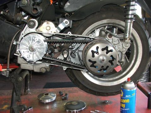 2008 Yamaha Zuma - A close-up view of a scooter's transmission components, including the drive belt and clutch, with tools and parts nearby.