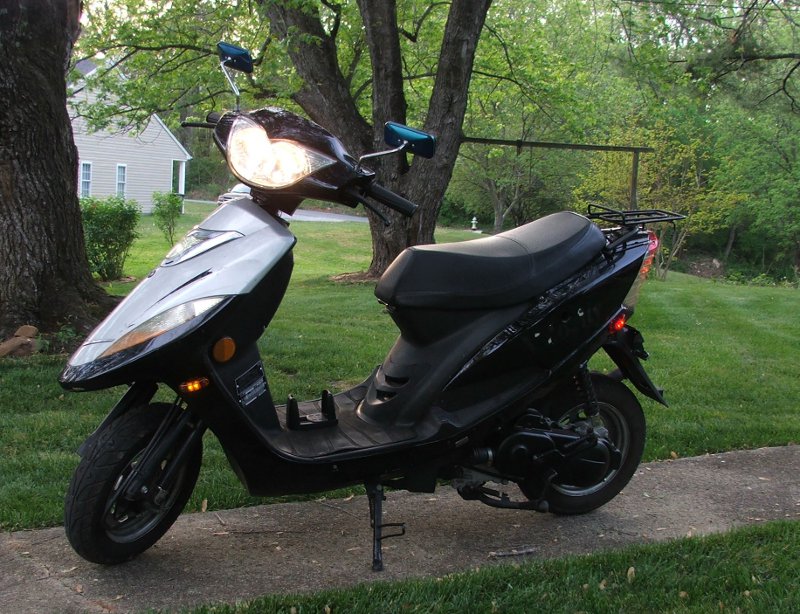Black scooter with silver front panel parked on a sidewalk