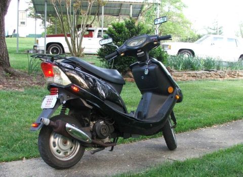 2008 Yamaha Zuma - A black scooter is parked on a sidewalk with a license plate on the rear.