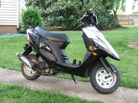 2008 Yamaha Zuma - A black scooter is parked on a sidewalk outdoors.