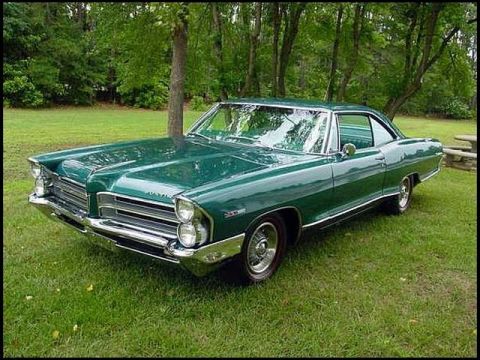 1991 Ford LTD Crown Victoria - A green 1963 Pontiac Catalina coupe is parked on a grassy lawn surrounded by trees.