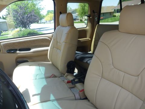 1997 Dodge 2500 - The interior of a truck shows tan leather seats and a view of the neighborhood through the windows.