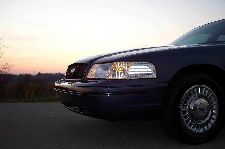 Dark blue Ford Crown Victoria front corner with headlight and grille at sunset