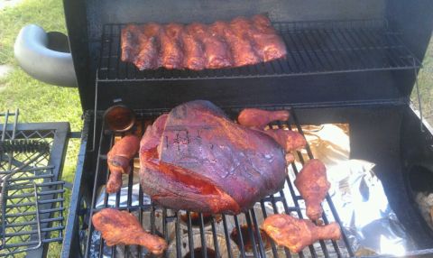 1989 Ford Bronco - A smoker grill is loaded with ribs and chicken legs, cooking over an open flame.