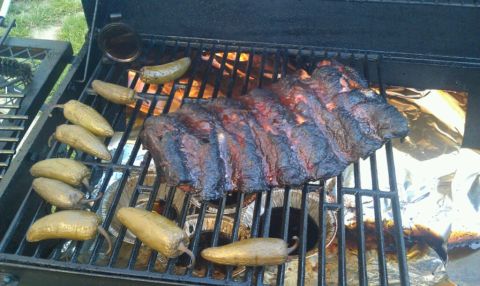 1989 Ford Bronco - A rack of ribs and several jalapeños are being grilled, with flames visible beneath the grates.