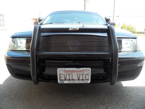 2003 Ford Crown Victoria - Close front shot of black Ford sedan with tubular push bar over billet grille, EVIL VIC plate