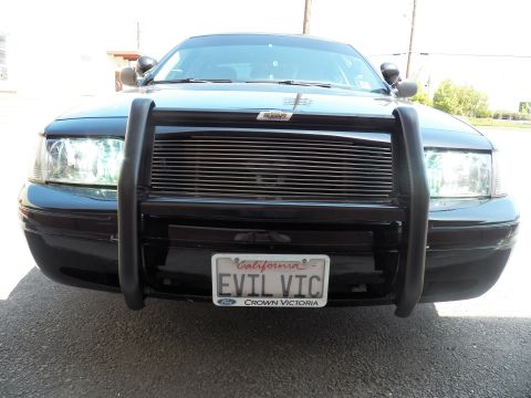 2003 Ford Crown Victoria - Front of dark Ford sedan with tubular push bumper over billet grille, EVIL VIC plate below