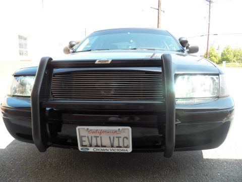 2003 Ford Crown Victoria - Black Ford sedan from a low angle, push bumper and billet grille framing EVIL VIC license