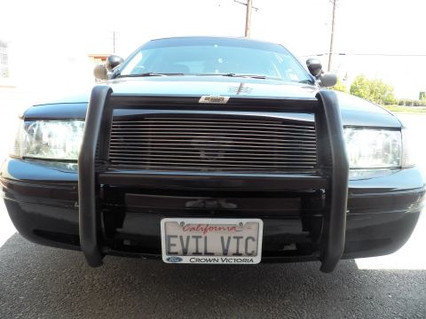 2003 Ford Crown Victoria - Low front shot of black Ford sedan, push bumper over billet grille above EVIL VIC plate