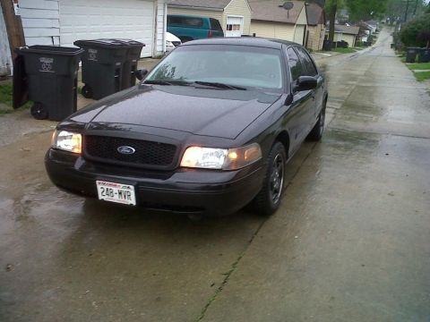 1999 Ford Crown Victoria - Front view of a black Ford Crown Victoria parked on a wet street.