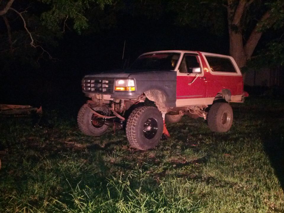 1987 Ford Bronco with front fenders painted different colors, lifted on jack stands