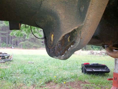 1987 Ford Bronco - Underside view of a rusty suspension component, likely from an older vehicle, with visible bolt heads.