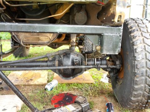 1987 Ford Bronco - The underside of a vehicle shows its heavy-duty axle and suspension components, with a tire visible on the right.