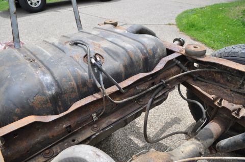 1986 Ford Bronco - The fuel tank and frame components are visible, showing significant rust and wear.