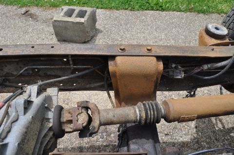 1986 Ford Bronco - Close-up view of the undercarriage of a vehicle, showing drivetrain components and frame.
