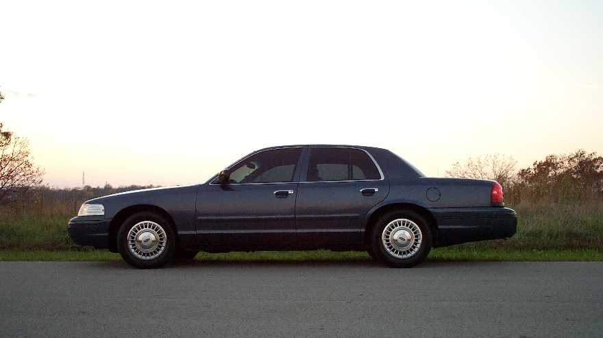 Dark blue Ford Crown Victoria sedan parked in side profile at dusk