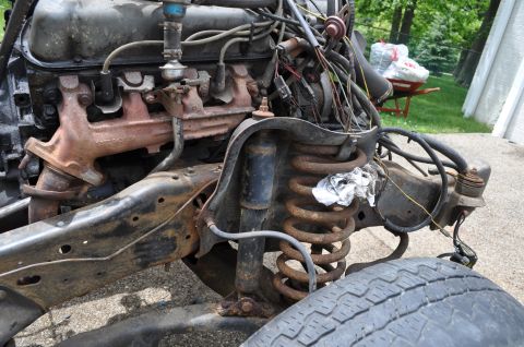 1986 Ford Bronco - Close-up view of rusty engine and suspension parts from a vehicle undergoing repair or awaiting repair.