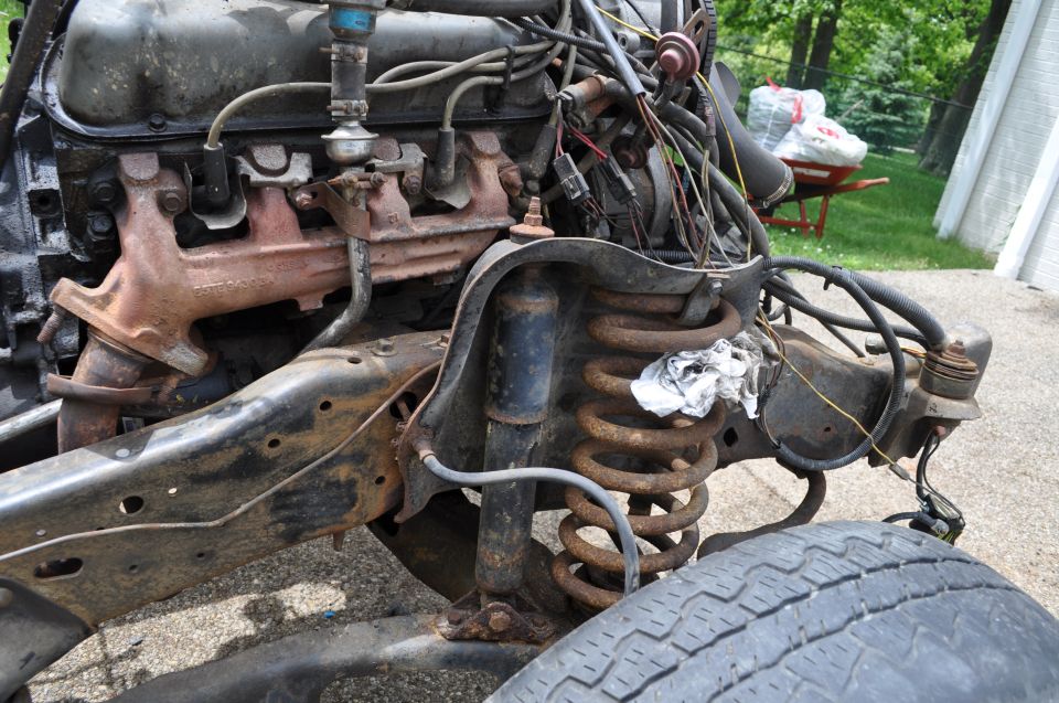 Engine block, exhaust manifold, and front suspension with coil spring and shock absorber. Some wiring is visible