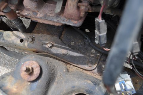 1986 Ford Bronco - Close-up view of engine bay components, including rusty metal brackets and electrical connectors.