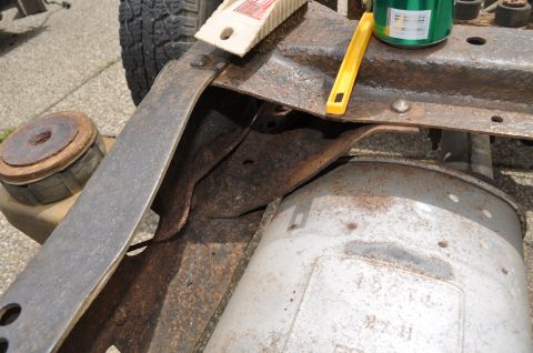 1986 Ford Bronco - Rusty vehicle frame and exhaust system with tools and a can of paint nearby.