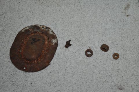 1986 Ford Bronco - Collection of rusty fasteners and a circular plate, possibly removed during rust removal.