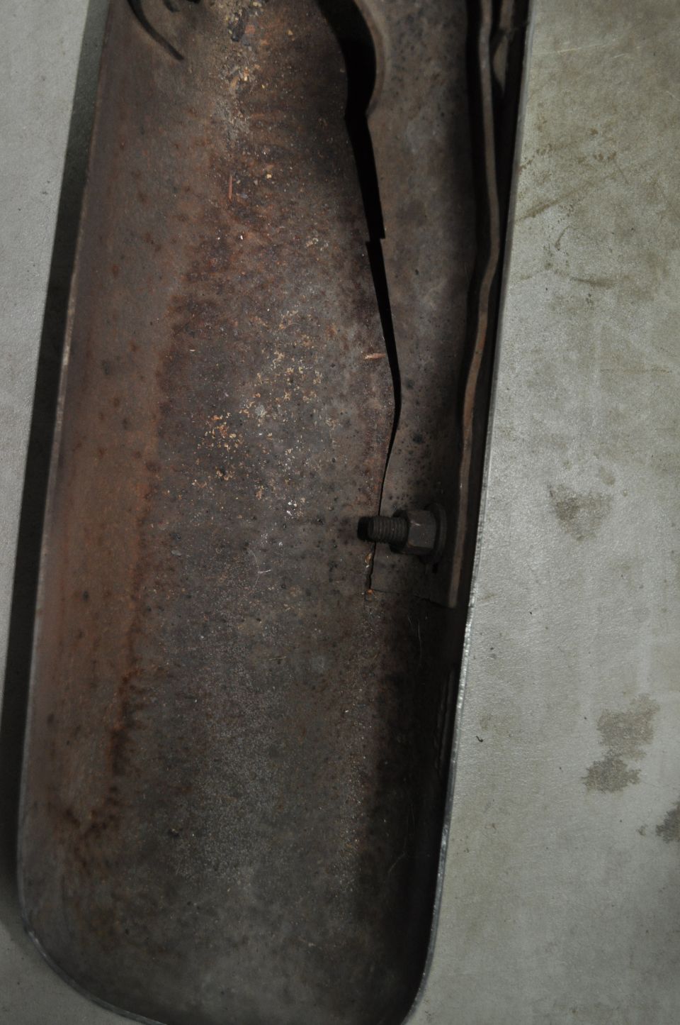 Rusted exhaust pipe with a crack and a bolt, showing significant corrosion
