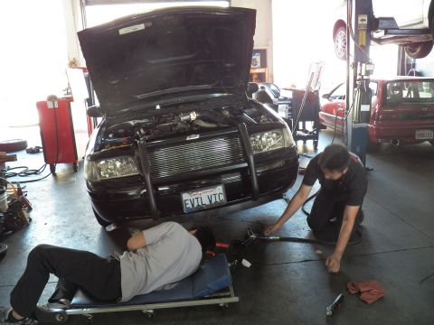 2003 Ford Crown Victoria - EVIL VIC California-plated Crown Vic on the shop floor as one tech lies on a creeper and another kneels by the front bumper