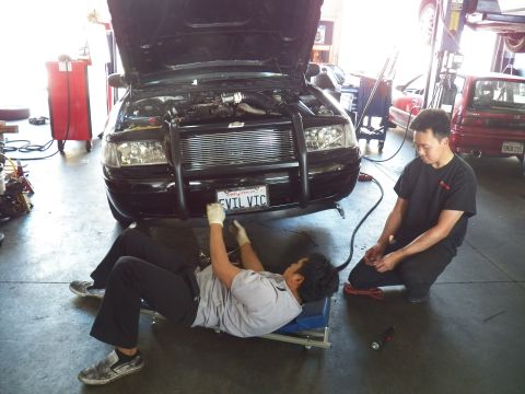 2003 Ford Crown Victoria - Two techs work the front of a black EVIL VIC Crown Victoria, hood raised over an intercooler and piping