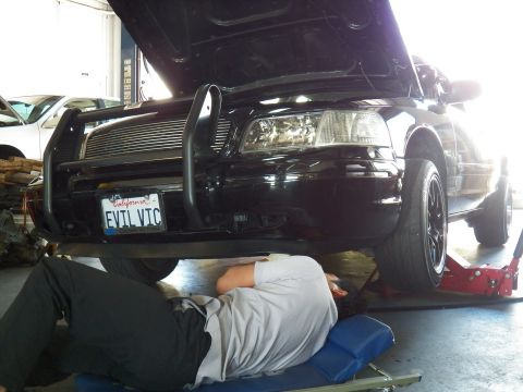2003 Ford Crown Victoria - Worker on a creeper under the front of the EVIL VIC Crown Vic, car raised on a red floor jack