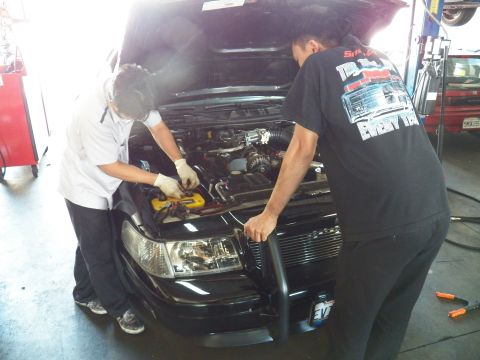2003 Ford Crown Victoria - Two mechanics work the engine bay of the EVIL VIC Crown Victoria, one in a graphic tee gripping the front