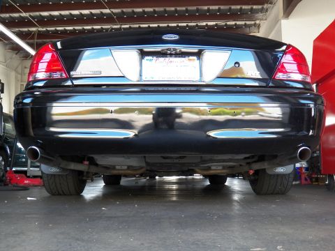 2003 Ford Crown Victoria - Black sedan rear end with polished chrome bumper, twin exhaust outlets and a California license plate.