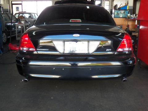 2003 Ford Crown Victoria - Black sedan rear showing SVT badge, Police Interceptor lettering, chrome bumper and dual exhaust tips.