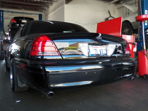 2003 Ford Crown Victoria - Rear three-quarter of a black Crown Victoria with chrome bumper and California plate inside a garage.